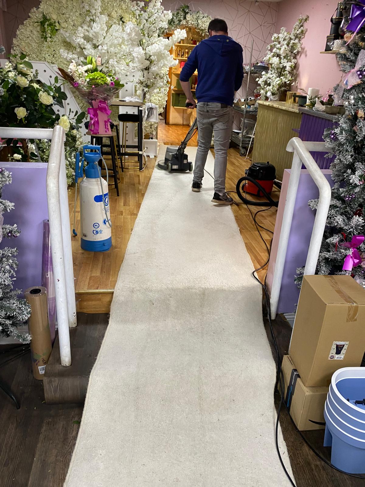 Clean pro using a machine to clean a rug in a flower shop