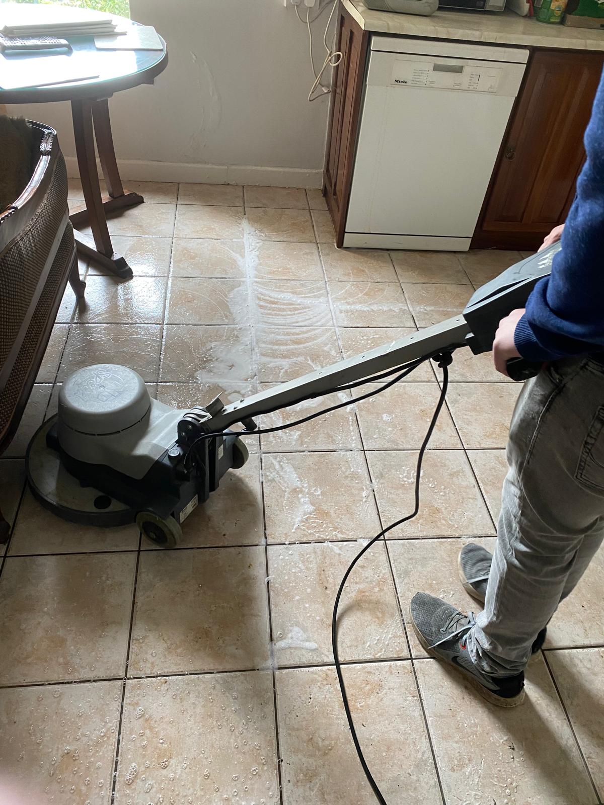 a worker cleaning a floor using a tile and grout cleaning machine