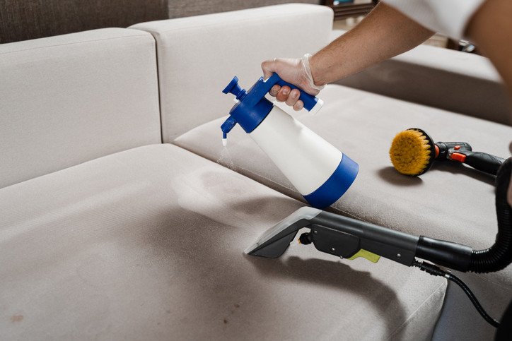 person using a machine to clean a couch.